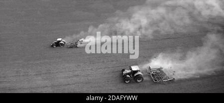aerial view of two agriculture tractors with plows. Plowing the field in sunny day, black and white Stock Photo