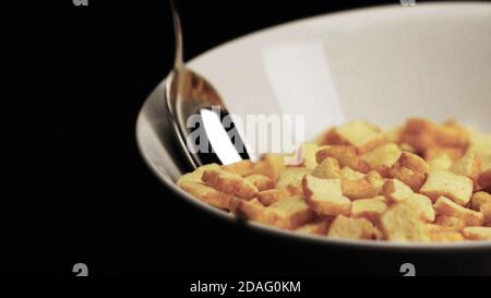 Close up of breakfast cornflakes in bowl with spoon in black copy space background. Stock Photo