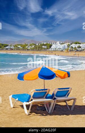 Vacation Concept Playa del Carmen beach Parasol sun lounger coastline sandy beach with sun shade parasol & loungers, Lanzarote, Canary Islands ,Spain Stock Photo