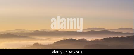 misty landscape at sunset, mountains rising from clouds of fog in the background, clear sky Stock Photo