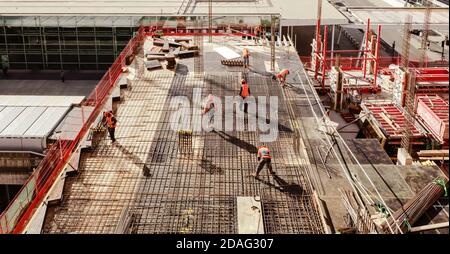 Top view of workers while fixing grid foundation bars in construction site roof. Stock Photo