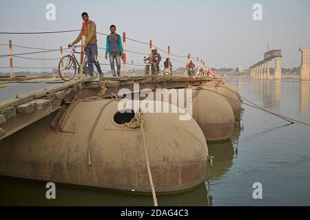 Varanasi, India, December 2015. People crossing a temporary bridge on the Ganges River, with the new one under construction in the background. Stock Photo