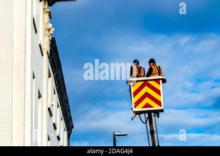 Two men working at height in a cherry picker set in front of a fresh blue sky Stock Photo