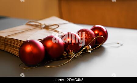 Christmas composition. Craft envelopes and Christmas red balls. Stack of letters tied with twine on blurred background Stock Photo
