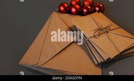Christmas composition. Craft envelopes and red balls on grey background Stock Photo