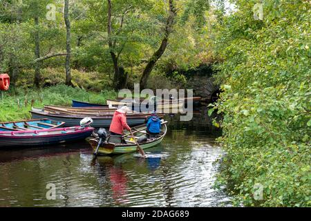 Senior couple paddling on a clinker boat or fishing row boat in small lake inlet in Killarney National Park, County Kerry, Ireland, Europe Stock Photo