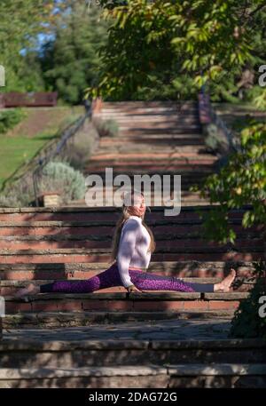 Middle-aged woman practicing a yoga routine in an outdoor environment . London UK. Stock Photo