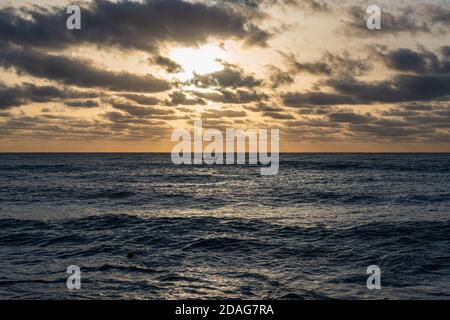 morning over a rough sea, dark clouds and wind foreshadow a storm, a lone sailing ship is at sea Stock Photo