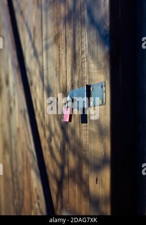 a small red padlock on a wooden door Stock Photo