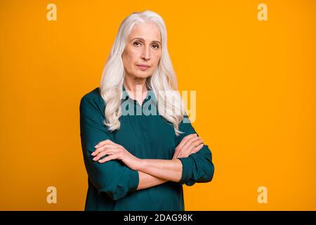 Photo of self-confident white haired bossy grandma lady hands crossed chief company ceo founder not smiling wear green shirt isolated bright yellow Stock Photo