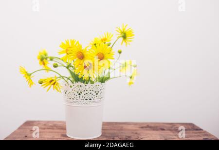 yellow flowers in a vase on a wooden background Stock Photo