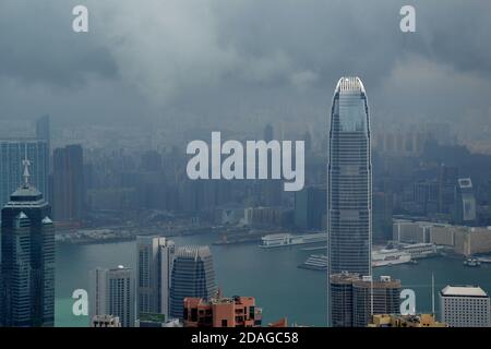 High modern buildings in fog and thick rain clouds of Hong Kong harbor from view point and green water Stock Photo