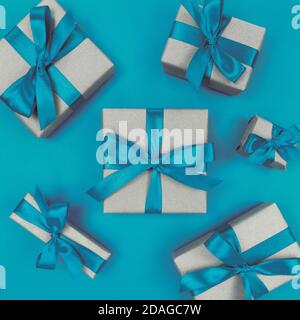 Gift boxes wrapped in craft paper with blue ribbons and bows. Festive monochrome flat lay. Stock Photo