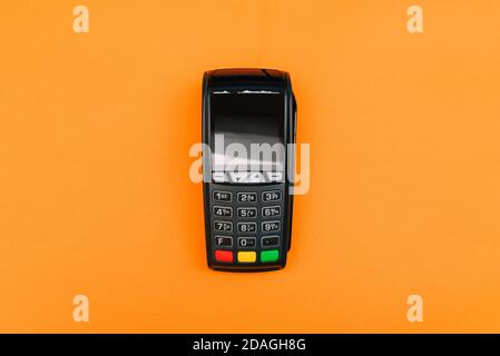 Payment terminal isolated on orange background. A contactless device for paying for purchases with a bank card or smartphone. E-commerce and business Stock Photo