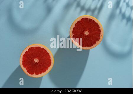Creative background  with two slice of  grapefruit  and shadows in minimal style. Creative summer layout. Horizontal orientation with space for text. Stock Photo