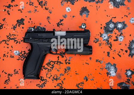 Modern black pistol on an orange scratched metal background. Weapons for defense and attack. Arming the police, army and special units. Stock Photo