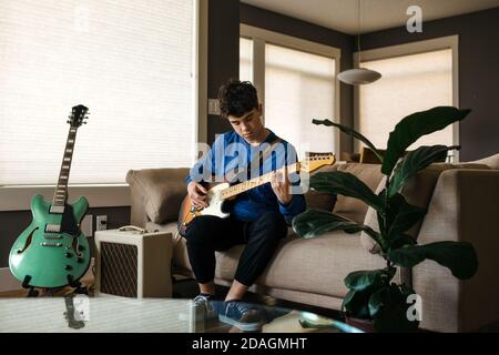 Teenager playing the guitar at home Stock Photo