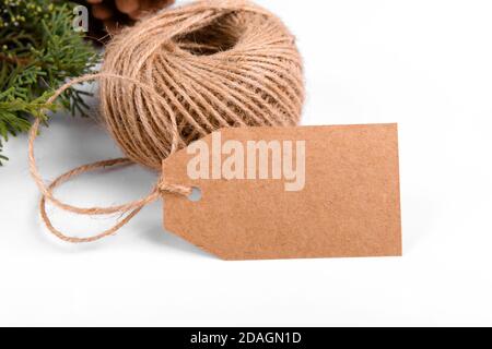 Christmas gift tag mock up of craft paper present label and green fir branch on white background Stock Photo