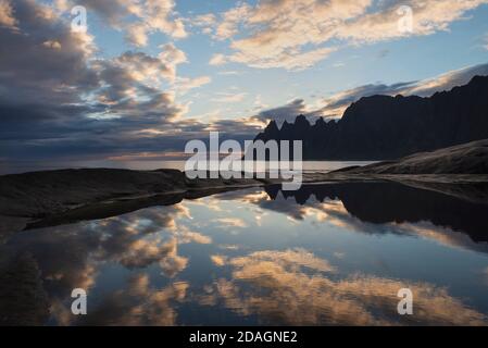 Reflection of Okshornen mountain peaks in tidal pool at Tungeneset viewpoint, Senja, Norway Stock Photo