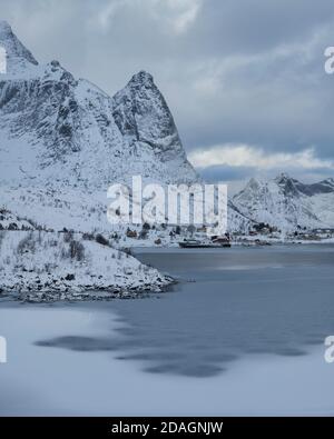 Mountians rise above frozen bay in Reine harbor, Reine, Moskenesøy, Lofoten Islands, Norway Stock Photo