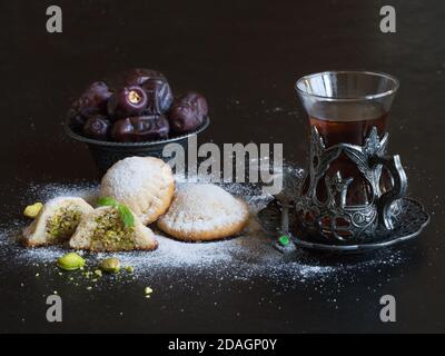 Egyptian cookies "Kahk El Eid" with dates and cup of tea served in a black table. Cookies of El Fitr Islamic Feast. Stock Photo