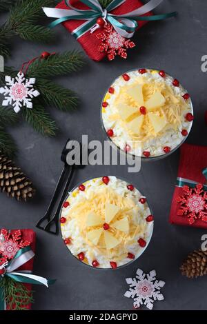 Festive salad with chicken, pineapple, cheese and eggs in portioned bowls on dark gray background. Top view. Vertical format Stock Photo