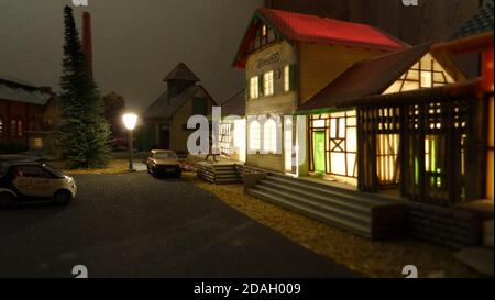 illuminated miniature train station with car in front model railway Stock Photo