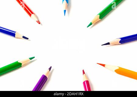 Circle of sharpened coloured pencils. The focus is on copy-space in the centre. Pencils point to your text or idea. Top view. Stock Photo