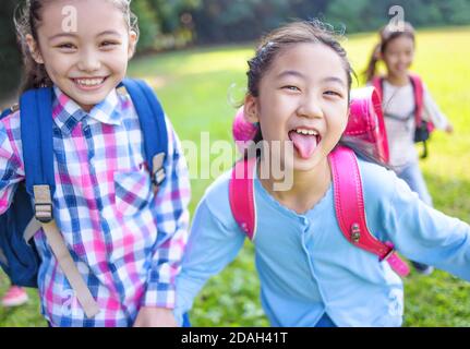 happy elementary school kids running on the grass Stock Photo