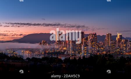 Fog drifting over the Granville Bridge as the Sun sets over the Skyline of Downtown Vancouver, British Columbia, Canada. Viewed from the South Shore o