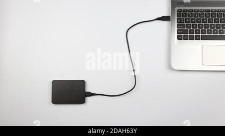 External hard drive connected to laptop on white surface. Concept for office, business, education and presentation Stock Photo