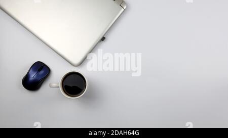 Desk with laptop, wireless mouse and a cup of coffee on white surface. Concept for office, business, education and presentation. Stock Photo