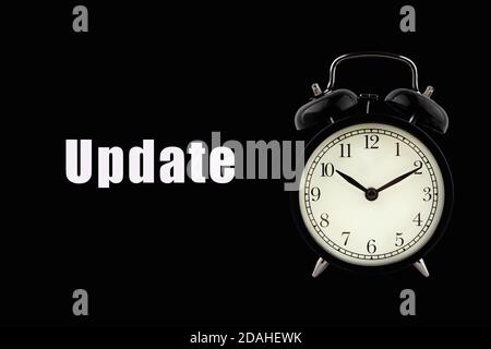 UPDATE text with alarm clock on black background. Business Concept Stock Photo