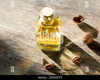 A bottle of walnut oil and walnuts on an old dark wooden table Stock Photo