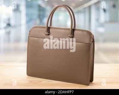 business women's bag of an office worker on wooden table on blurred background of the office. business leather briefcase businesswoman. accessories fo Stock Photo