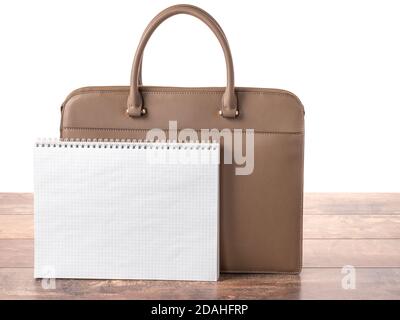 mockup blank notebook on spiral against the background of business briefcase bag. mockup office work concept. wooden table. isolated on white Stock Photo