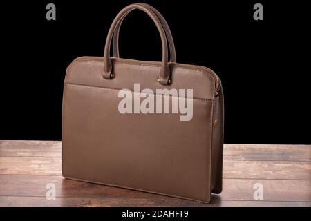 model of a brown business office leather bag on wooden table isolated on black background. Business woman Briefcase Stock Photo