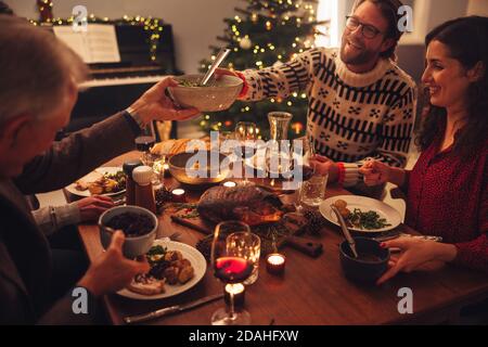 Family having a Christmas eve dinner together inside their home. European family enjoying dinner at Christmas eve. Stock Photo