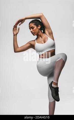 Portrait of female athlete doing workout on white background. Fit woman doing stretching exercises. Stock Photo