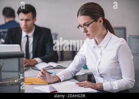 Successful woman in glasses with pencil working with papers. Stock Photo