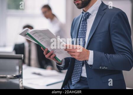 Man in suit studying document, no face visible Stock Photo