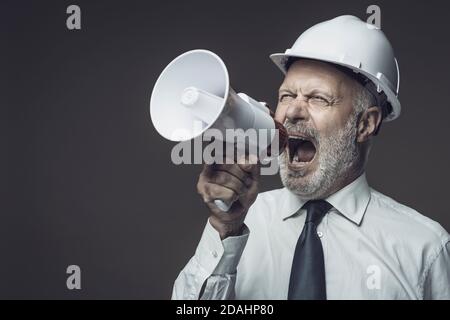 Senior engineer and businessman shouting into a megaphone, marketing and communication concept Stock Photo