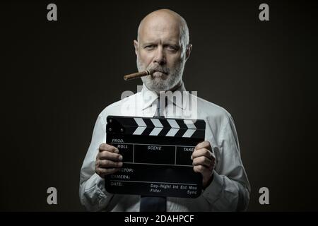 Middle-aged film director holding a clapperboard, cinematography and film industry concept Stock Photo