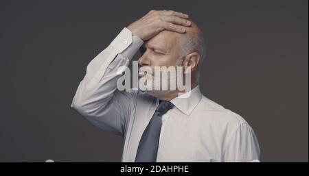 Disappointed businessman touching his forehead, he has made a mistake and feels regretful Stock Photo