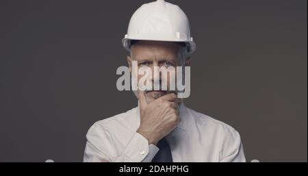 Confident senior businessman and engineer thinking with hand on chin Stock Photo