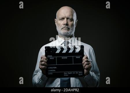 Middle-aged film director holding a clapperboard, cinematography and film industry concept Stock Photo