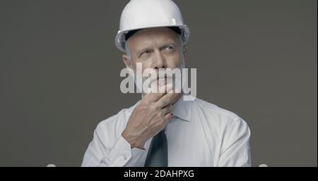 Confident senior businessman and engineer thinking with hand on chin Stock Photo