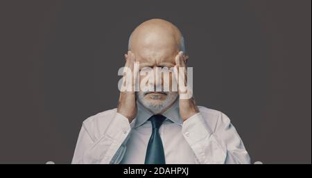 Exhausted stressed middle-aged businessman having a bad headache, he is tired and overworked Stock Photo