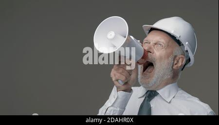 Senior engineer and businessman shouting into a megaphone, marketing and communication concept Stock Photo