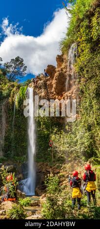 Unrecognizable people descending waterfall using ropes Stock Photo